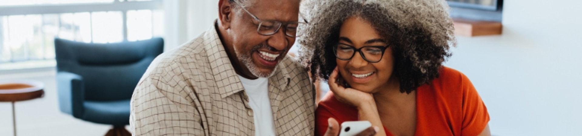 Couple looking at a phone while sitting at a desk